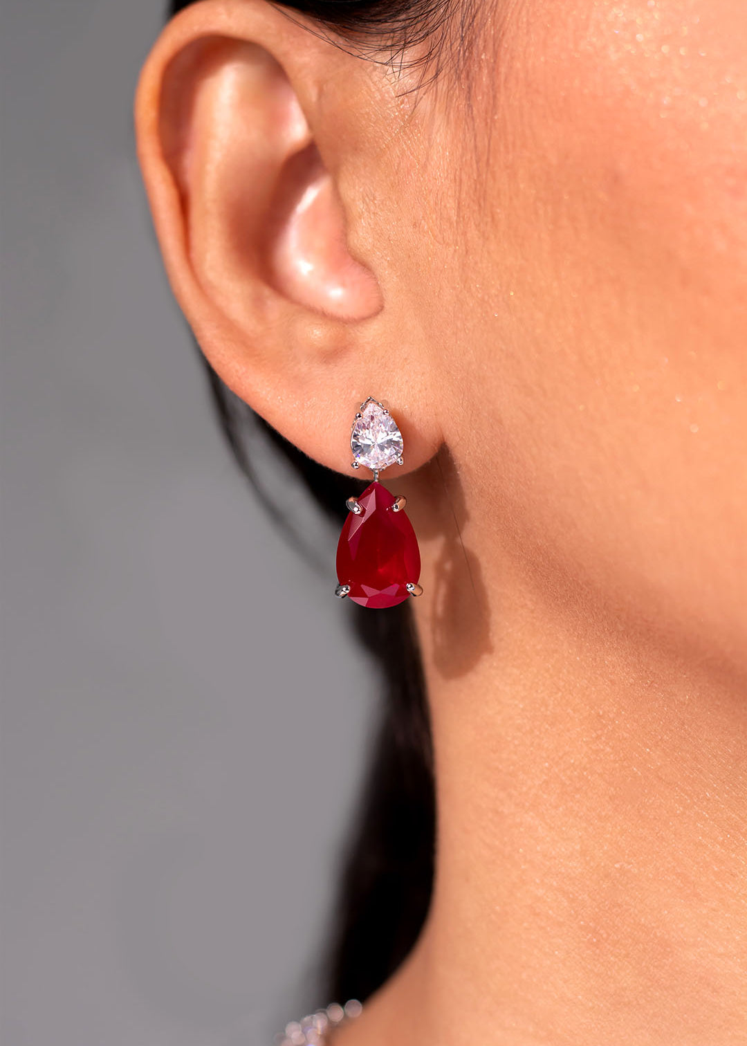 Ruby red teardrop drop earring with clear CZ stud worn on the ear – Duavaa
