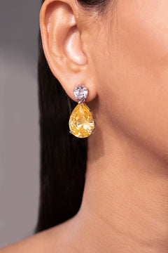 Yellow pear-cut drop earring below a round white stud worn on model's ear – Duavaa