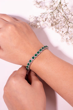 Emerald green cushion-cut halo tennis bracelet being fastened on wrist – Duavaa