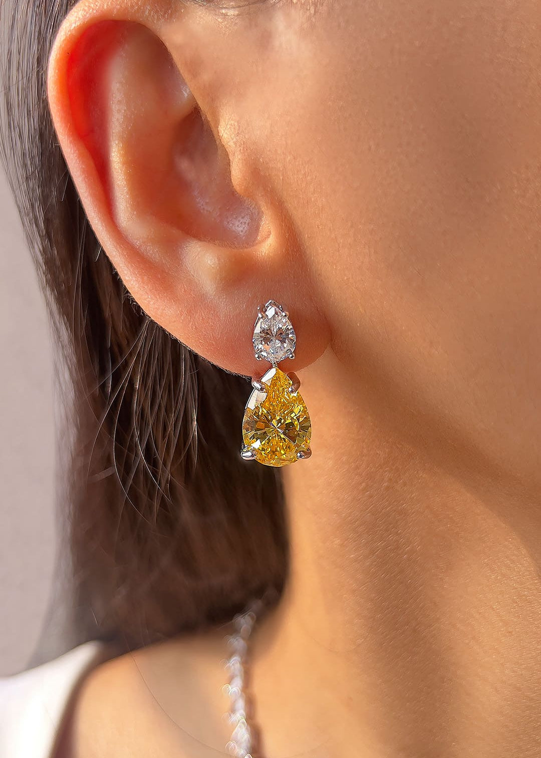 Yellow pear-cut crystal drop earrings worn on the ear – Duavaa