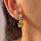 Yellow pear-cut crystal drop earrings worn on the ear – Duavaa