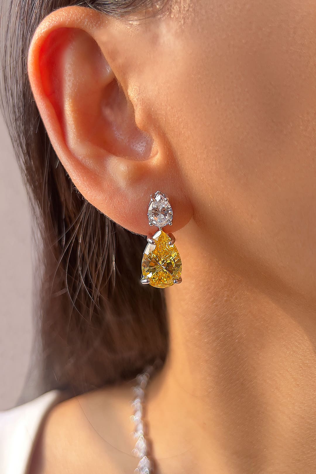 Yellow pear-cut crystal drop earrings worn on the ear – Duavaa
