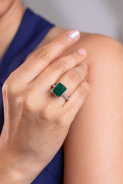Green emerald-cut solitaire ring on a pave band worn on a model's finger – Duavaa