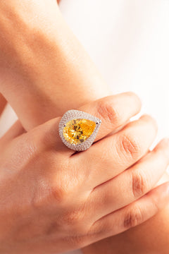 Yellow pear-cut cocktail ring with crystal pave halo on a model's finger – Duavaa