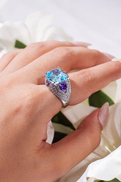 Aqua blue cushion-cut ring with purple trillion sides worn on a model's finger – Duavaa
