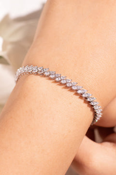White pear-cut single-row tennis bracelet worn on wrist with white flowers behind – Duavaa