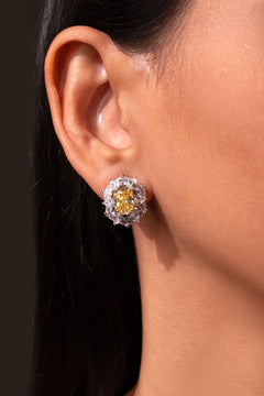 Yellow cushion-cut stud earring framed by clear CZ halo worn on a model's ear – Duavaa