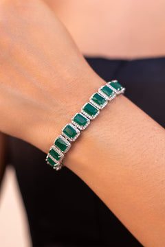 Emerald green emerald-cut tennis bracelet with pavé halos worn on model's wrist – Duavaa