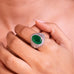 Emerald green oval-cut cocktail ring with pave halo worn on a model's finger – Duavaa