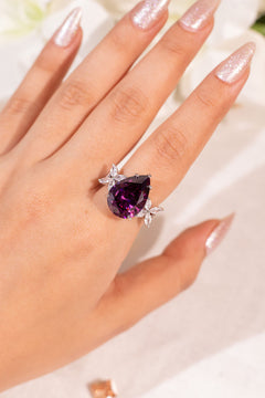 Purple pear-cut crystal ring with marquise petal accents worn on hand, close-up – Duavaa