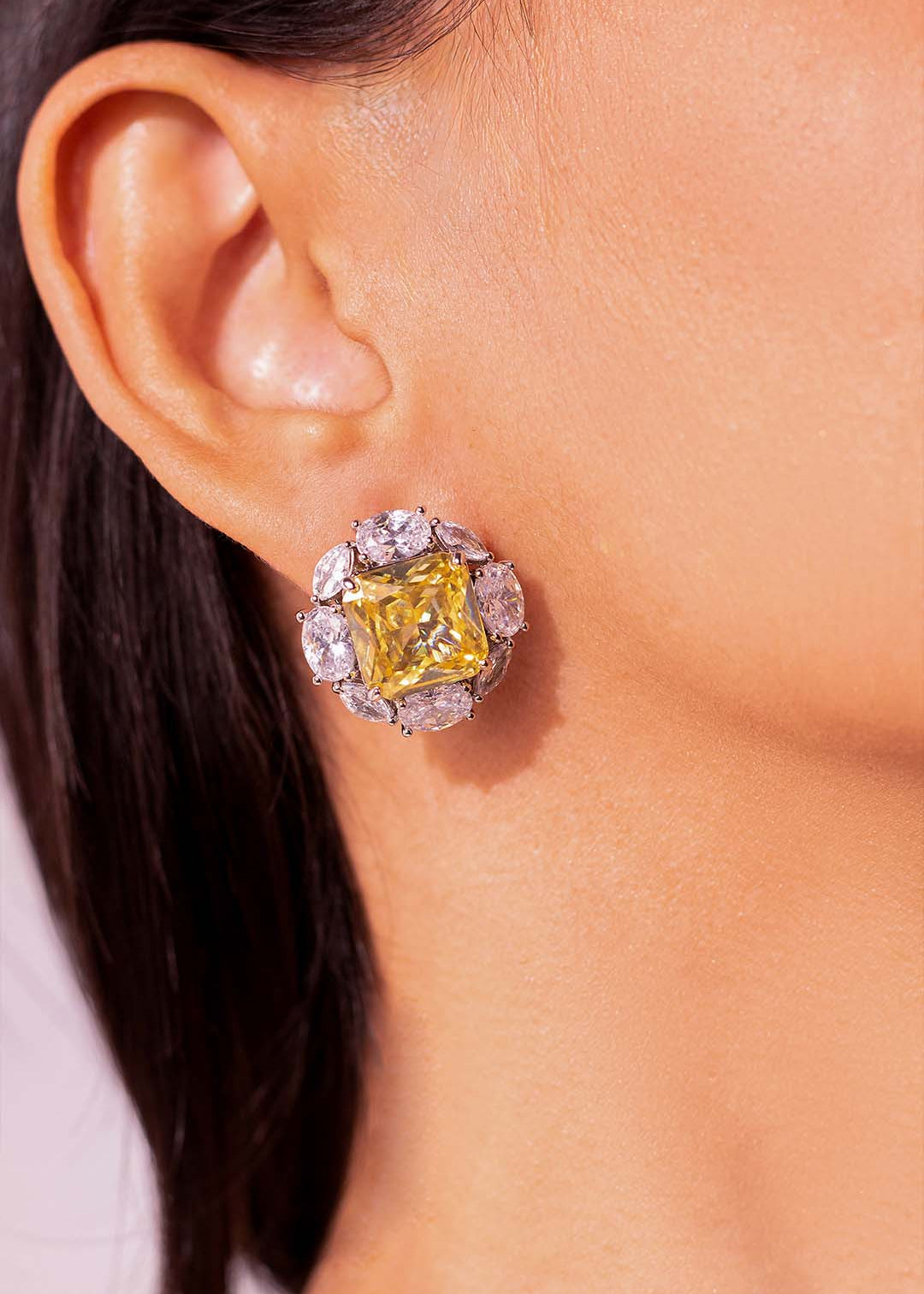 Close-up of yellow square-cut CZ halo stud earring worn on a model's ear – Duavaa