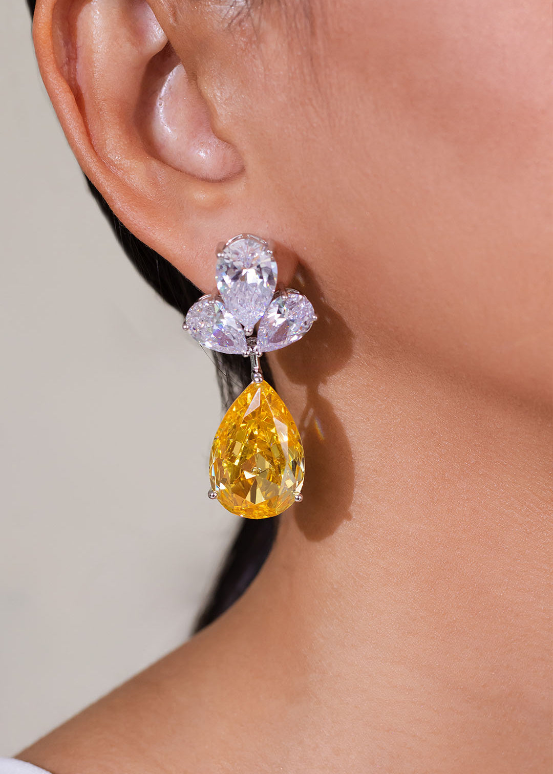 Golden yellow teardrop crystal drop earring worn on model's ear – Duavaa