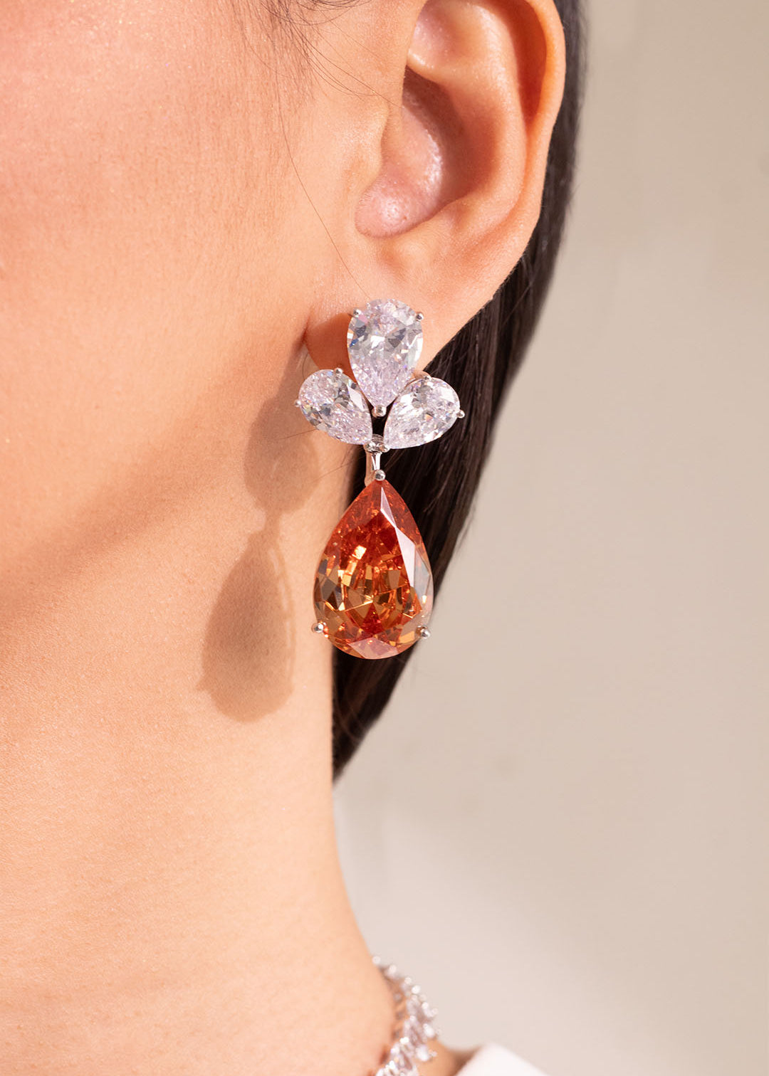 Champagne pear-cut drop earring with clear crystal cluster worn on model's ear – Duavaa