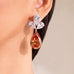 Champagne pear-cut drop earring with clear crystal cluster worn on model's ear – Duavaa