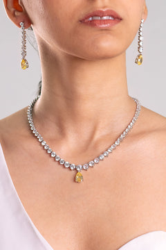 Yellow pear-drop CZ pendant necklace and matching drop earrings worn by a model – Duavaa