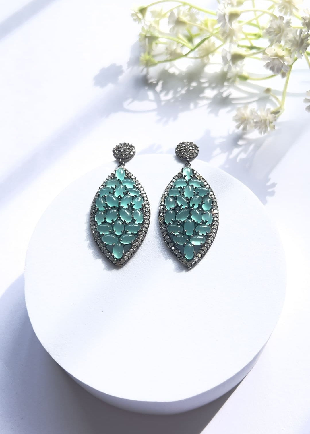 Blue chalcedony marquise sterling silver drop earrings flat-lay on white disc with flowers – Duavaa